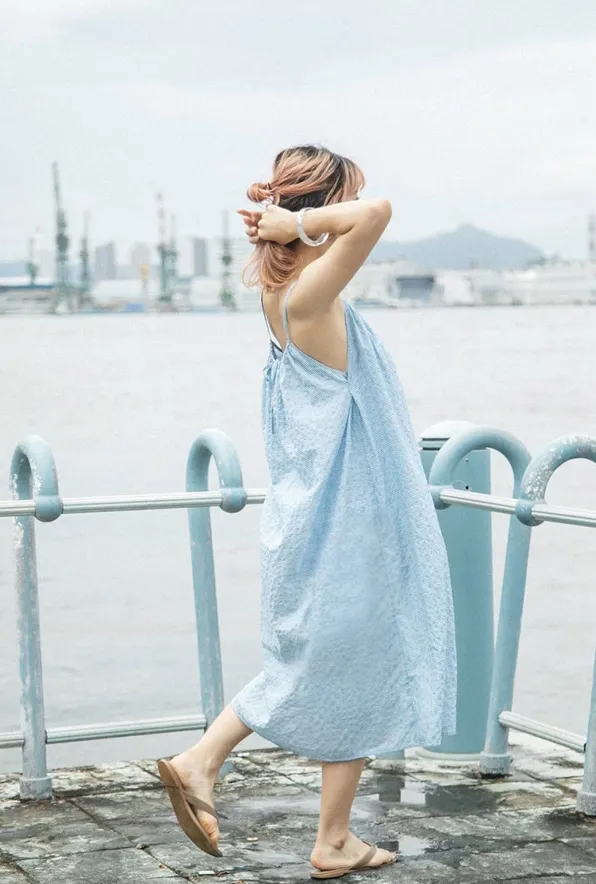 海辺で播州織の水色ワンピースを着た女性