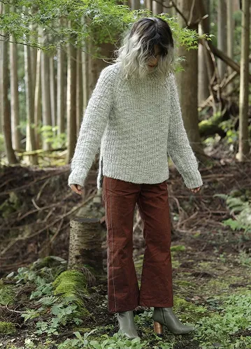 ワインカラーでアレンジワインダーの生地を使用したパンツを履いた女性が森の中で立っている