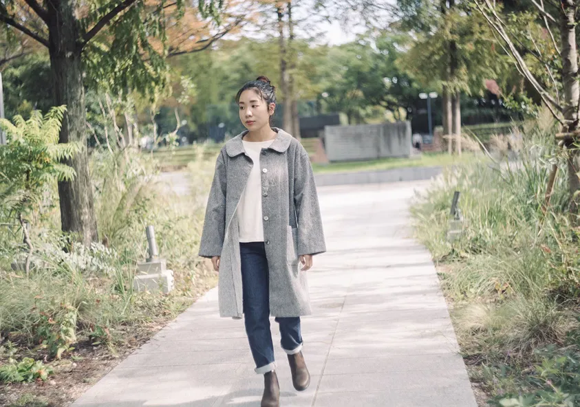 播州織のアウターを羽織り道を歩く女性