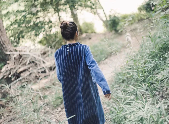 モール素材のワンピースを着た女の子が森の中を歩いている後ろ姿